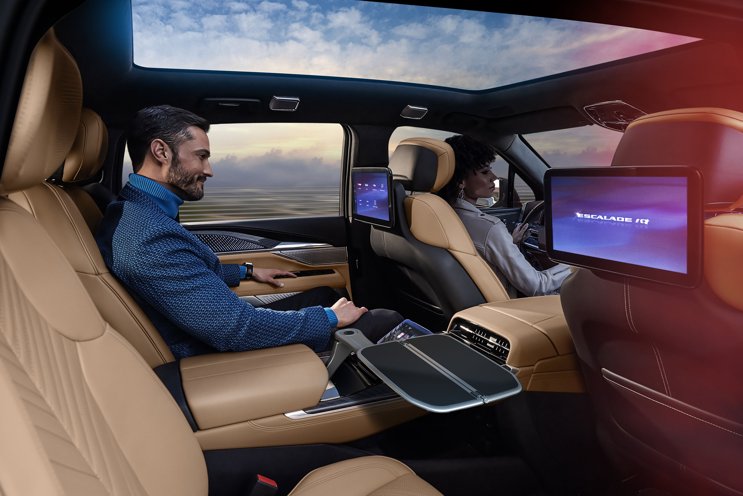 2025-cadillac-escalade-iq-sport-010-copy Man sitting in Executive Second Row of Cadillac ESCALADE IQ with backseat screens.
