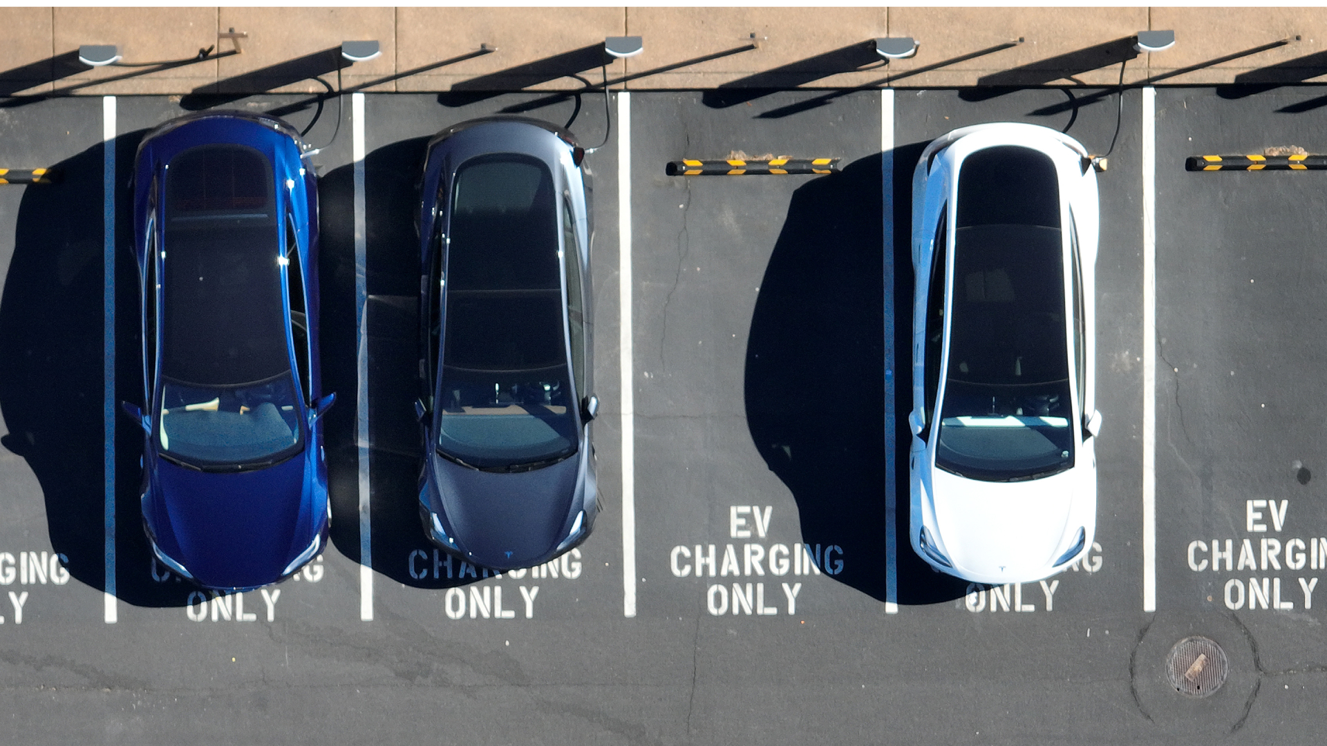 chargers-getty-1 CORTE MADERA, CALIFORNIA - FEBRUARY 15: In an aerial view, Tesla cars recharge at a Tesla charger station on February 15, 2023 in Corte Madera, California. Electric car company Tesla is partnering with the U.S. federal government to expand electric vehicle charging infrastructure in the United States. Tesla announced plans to open an estimated 7,500 of its Tesla Superchargers in the country to all brands of electric vehicles by the end of 2024.