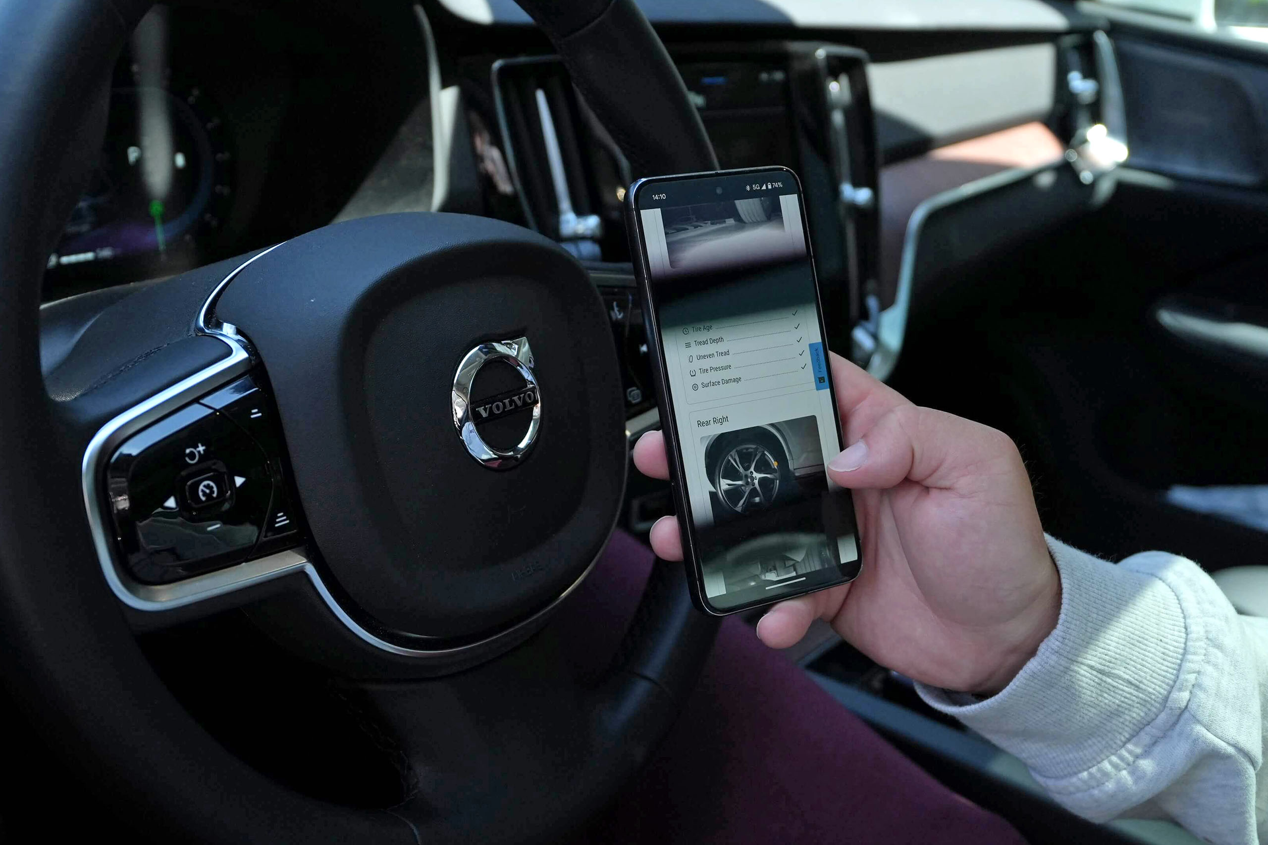 conditionreportphone-copy Person in car holds smartphone showing UVeye web app that highlights damage to a rented vehicle.