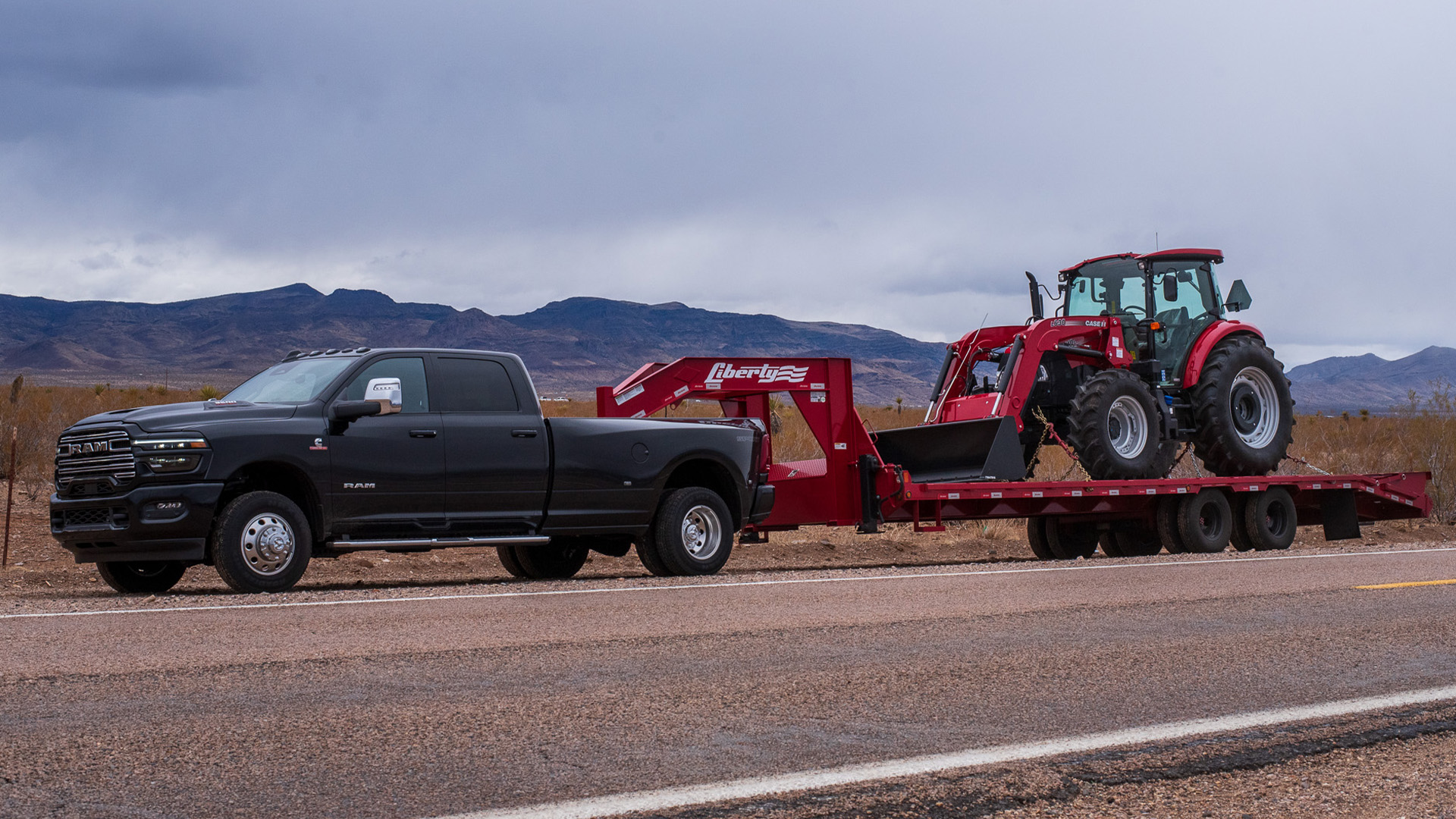 ram-hd-warranty-hero-1-1 Ram HD towing a trailer with a tractor loaded on it.
