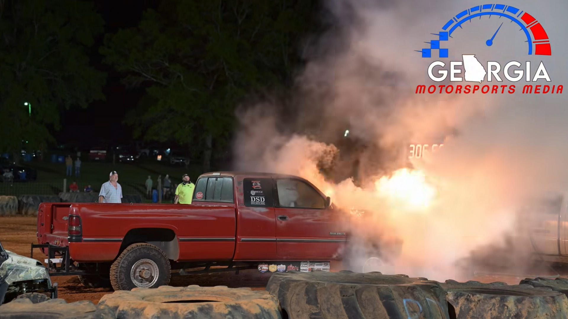 A safety crew works to extinguish a flaming Dodge Ram pickup.